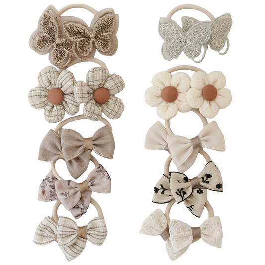 Set of decorative hair ties with floral and bow designs on a light background