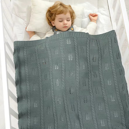 Child sleeping under a textured green blanket in a crib