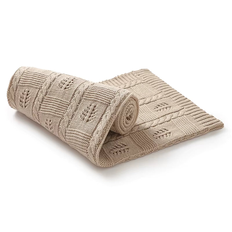 Beige knitted blanket with cable pattern on a white background