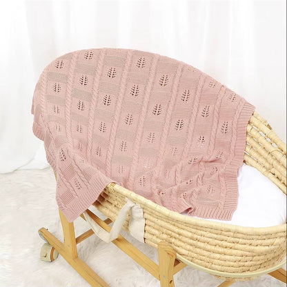 Pink textured blanket draped over a wicker chair on a white background