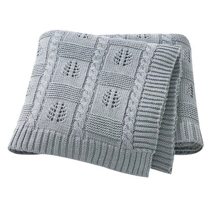 Gray knitted blanket with leaf pattern on a white background