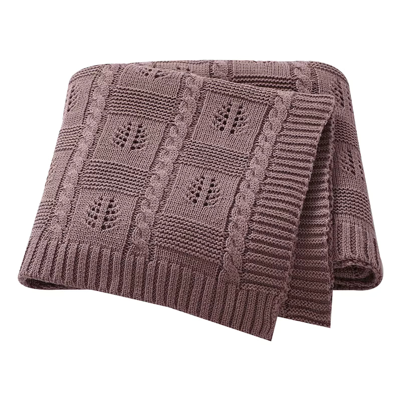 Brown knitted blanket with a leaf pattern on a white background
