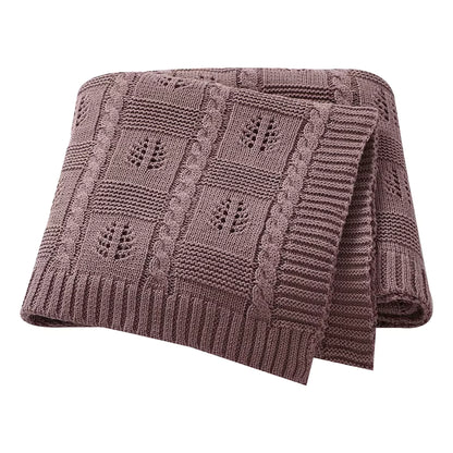 Brown knitted blanket with a leaf pattern on a white background