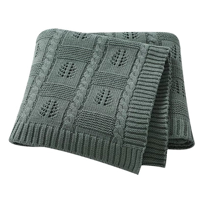 Green knitted blanket with a leaf pattern on a white background