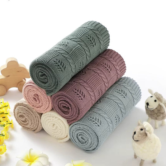Folded heirloom knit baby blanket with detailed vintage leaf pattern.