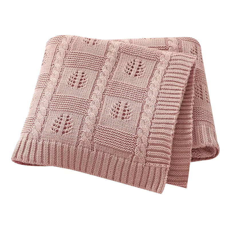 Pink knitted blanket with a geometric pattern on a white background