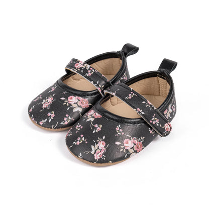 Front angled view of black cottagecore infant floral Mary Jane shoes with thin flexible rubber soles.