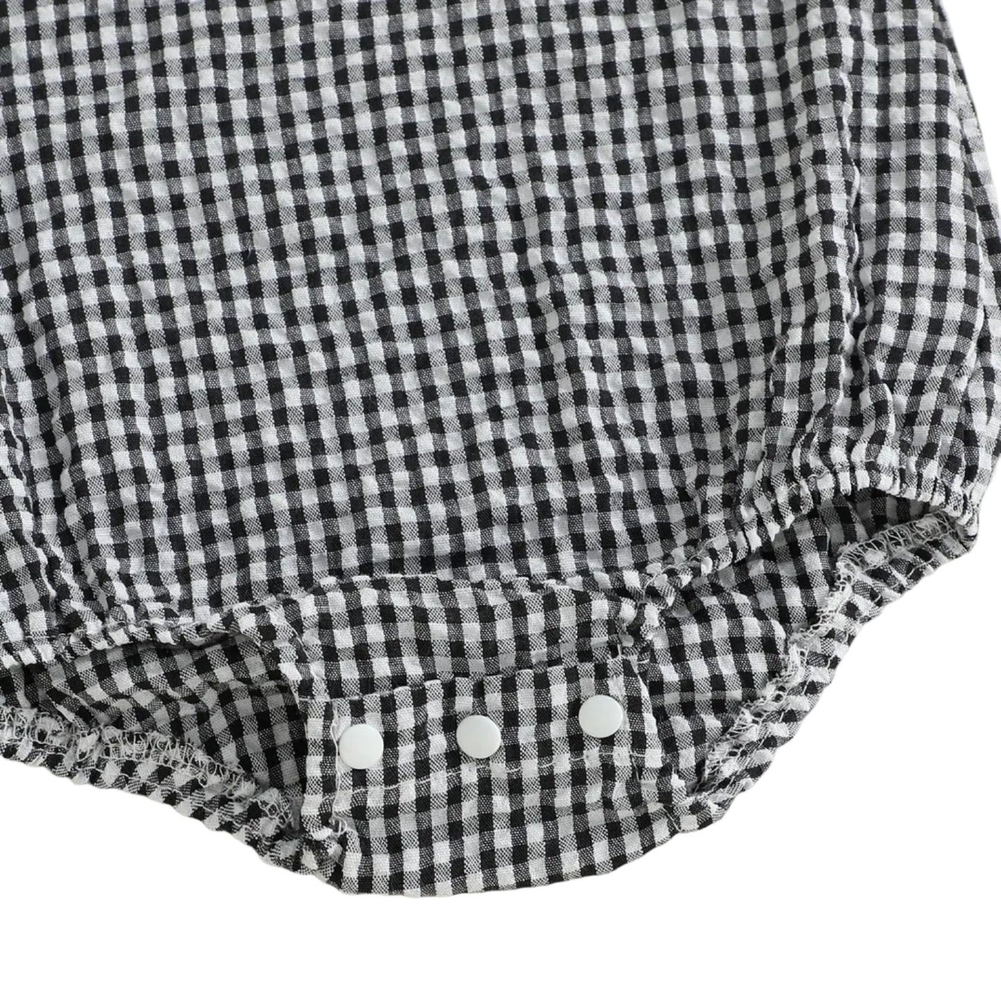 Detailed close-up view of the secure three-snap bottom closure on the black and white gingham baby romper, designed for easy diaper changes.