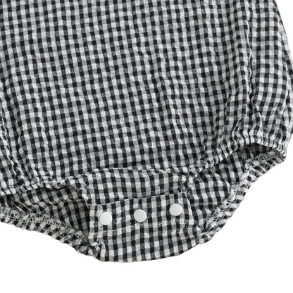 Detailed close-up view of the secure three-snap bottom closure on the black and white gingham baby romper, designed for easy diaper changes.