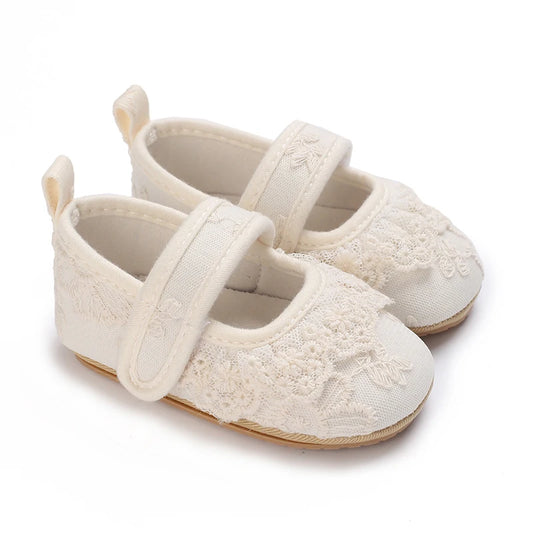 Infant girl floral lace cream Mary Jane shoes with adjustable strap and soft sole for special occasions.