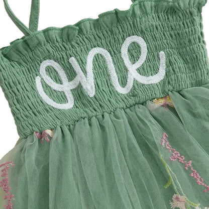 Close-up of the high-quality white chain-stitch "one" embroidery on the comfortable green smocked bodice and floral tulle layers.