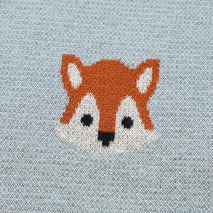 Detailed close-up of knitted orange fox face motif on light blue cotton baby blanket