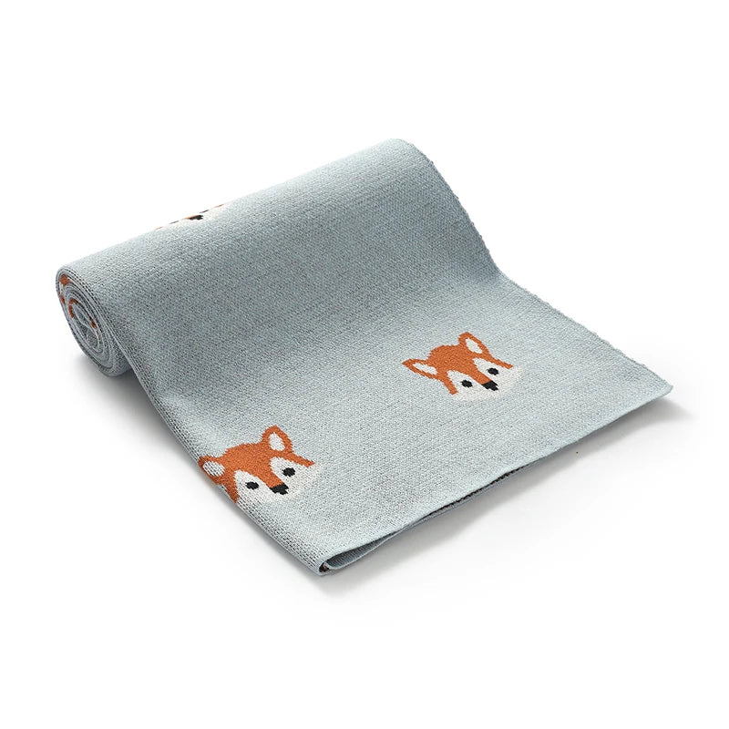 Light blue soft knitted baby blanket with fox pattern laid out flat
