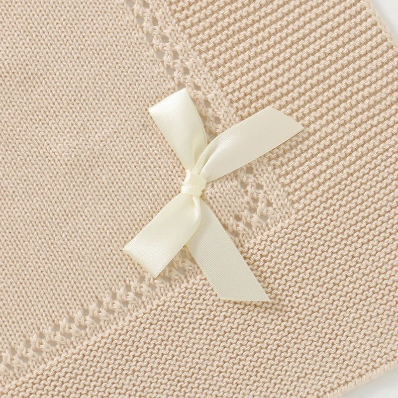 Detailed view of elegant bow accent on an oatmeal knitted cotton receiving blanket