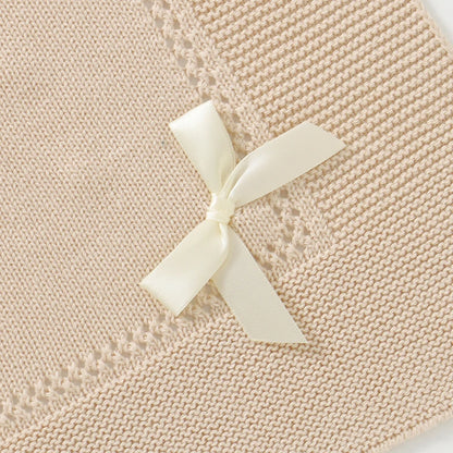 Detailed view of elegant bow accent on an oatmeal knitted cotton receiving blanket
