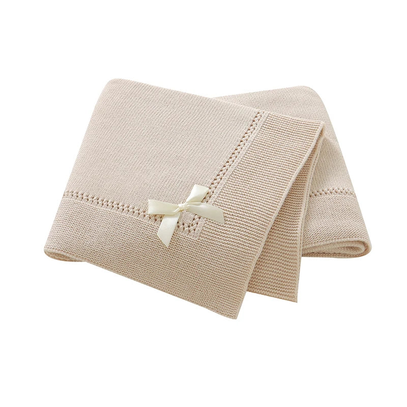 Folded oatmeal 100% cotton soft knit baby blanket featuring ribbon bow accent