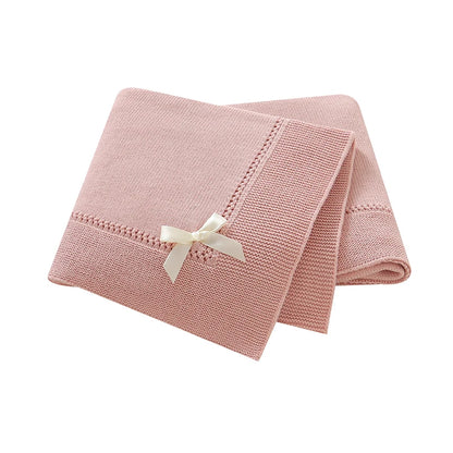 Soft pink 100% cotton knit baby receiving blanket with bow accent folded on white background