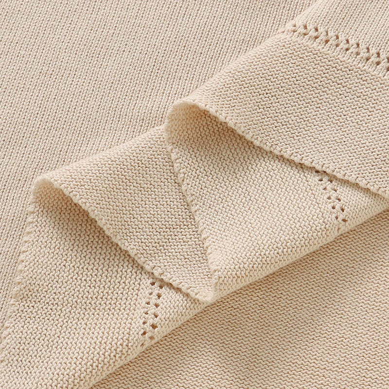 Close-up of fine cotton knit weave and finished hemmed border on oatmeal baby blanket