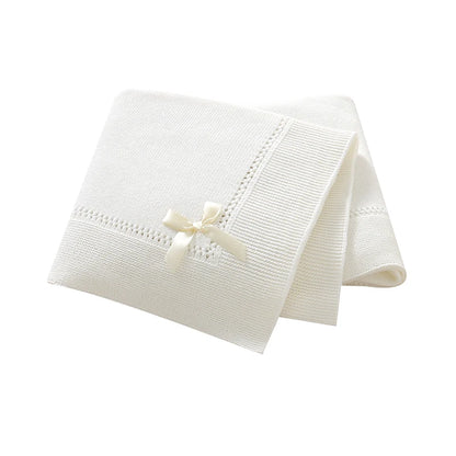 White 100% cotton soft knit baby receiving blanket with bow accent folded on white background