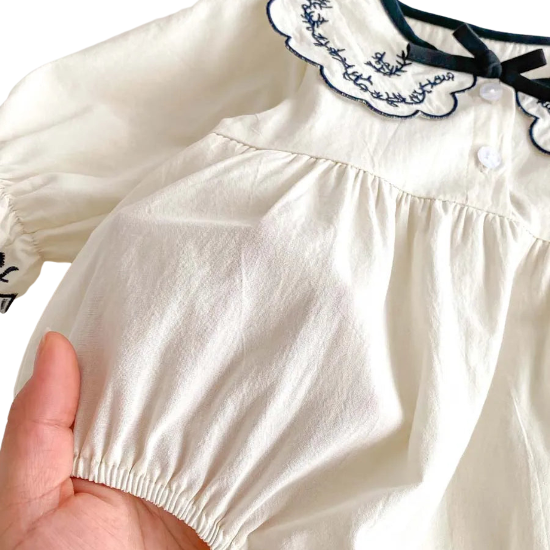 A close-up view of the soft, breathable 100% woven cotton fabric on the ivory bubble romper.