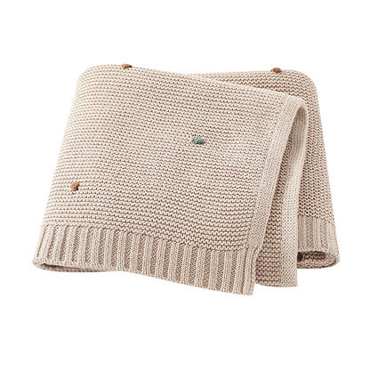 Gender-neutral Toasted Almond colored knitted baby blanket made of 100% cotton with textured pips.