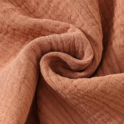 Close-up detail of the premium swaddled double-gauze 100% cotton muslin fabric texture highlighting its soft breathable crinkle weave.