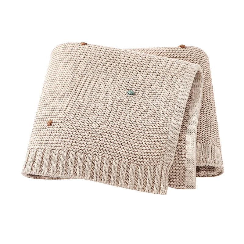 Main product image of a Toasted Almond colored 100% cotton knitted baby blanket, folded neatly to display its soft popcorn dot texture and ribbed edges.