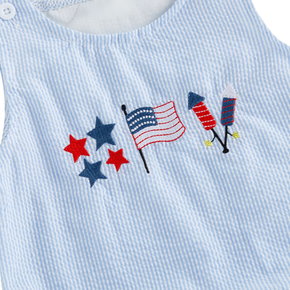 Close-up detail of the American flag, red and blue stars, and firecracker embroidery on the blue and white striped baby romper.