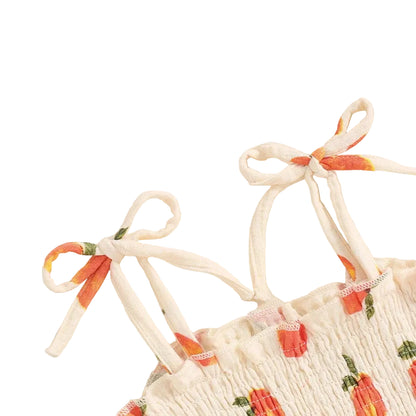 Close-up of the adjustable tie-strap shoulders on the baby girl peach print romper dress.