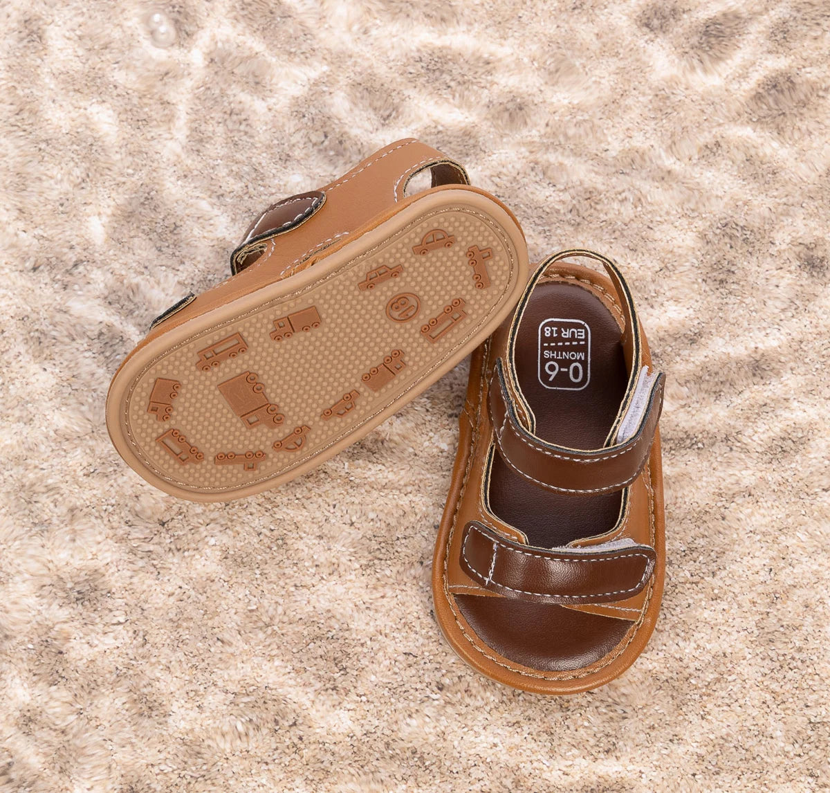 Bottom of brown baby sandals showing the anti-slip PVC sole with car and truck tread patterns.