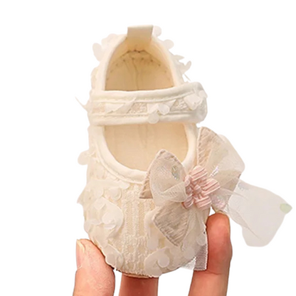 Front perspective of Kidsely antique white princess first walker crib shoe held in hand.
