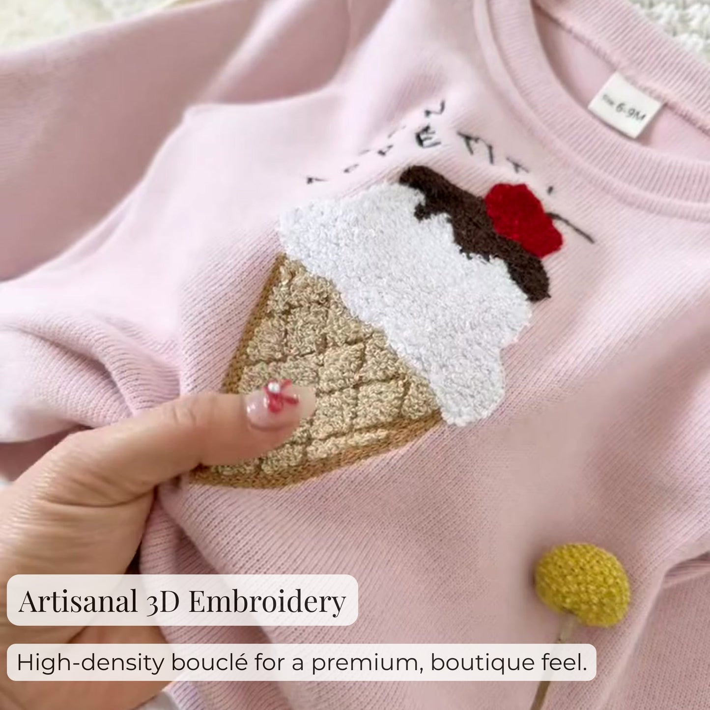 Macro close-up shot showing the high-quality, high-density textured bouclé ice cream applique with artisanal 3D embroidery detail on the pink sweatshirt.