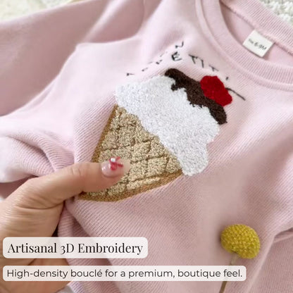 Macro close-up shot showing the high-quality, high-density textured bouclé ice cream applique with artisanal 3D embroidery detail on the pink sweatshirt.