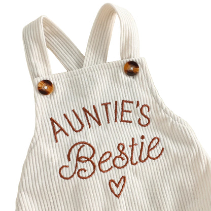 Close-up of the front chest of the beige baby romper highlighting the high-quality brown "Auntie's Bestie" text and heart embroidery
