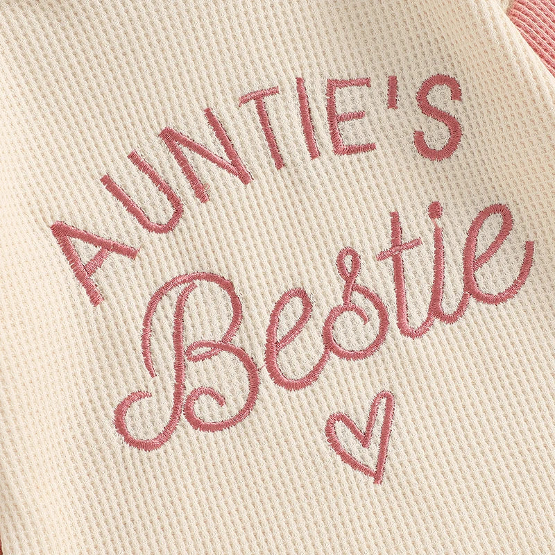 Close up of the Auntie's Bestie pink embroidered lettering and heart on cream waffle knit fabric.