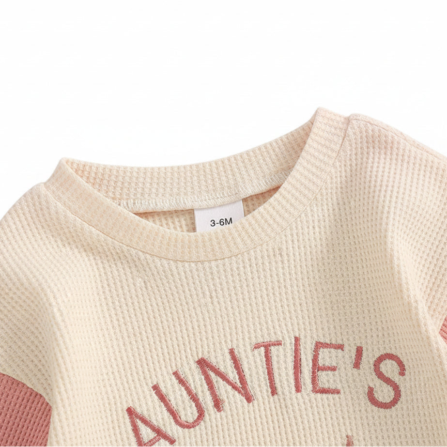 Close up of the round neckline on the pink and cream waffle knit baby romper.