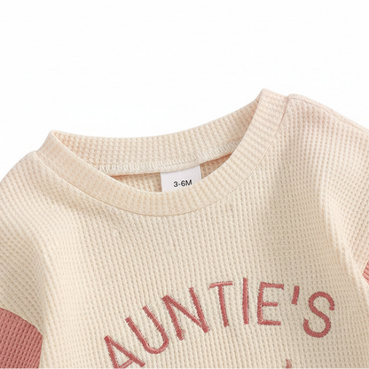 Close up of the round neckline on the pink and cream waffle knit baby romper.