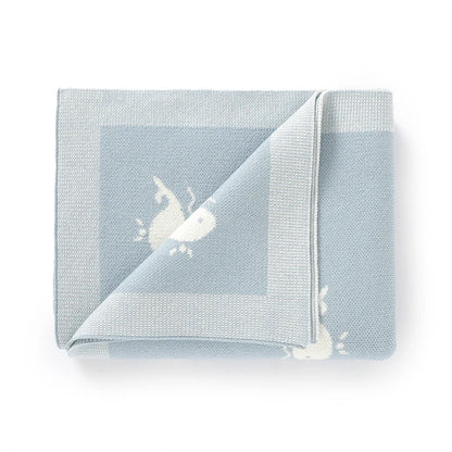 Flat folded Kidsely baby blue knit swaddle blanket featuring a cute ocean whale design