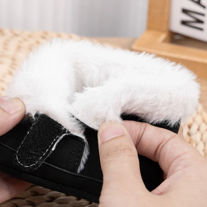 Close-up of a hand opening the side hook-and-loop closure of a black baby crib boot to show the thick plush fleece lining.