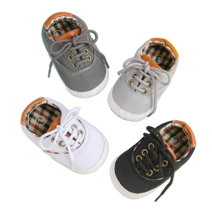 A collection of baby boy canvas first walker shoes in multiple colors including Heritage Tan, Navy Blue, and Grey, featuring soft soles and iconic plaid lining for infants and toddlers 0-18M.