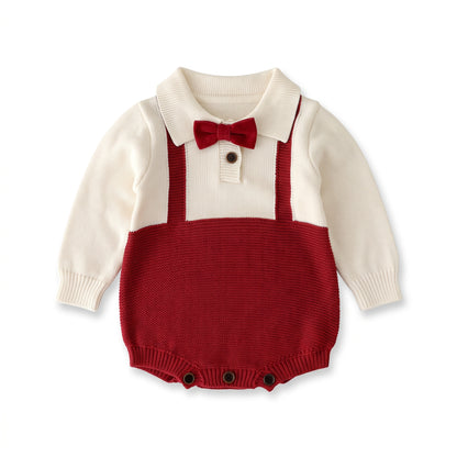 Flat lay of a baby boy formal knit romper featuring a cream top, red faux suspenders, peter pan collar, and an attached red bow tie.