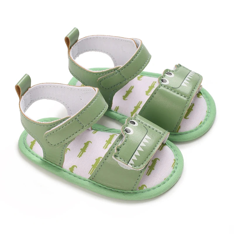Pair of green baby boy crocodile sandals featuring a stitched gator face and adjustable straps.