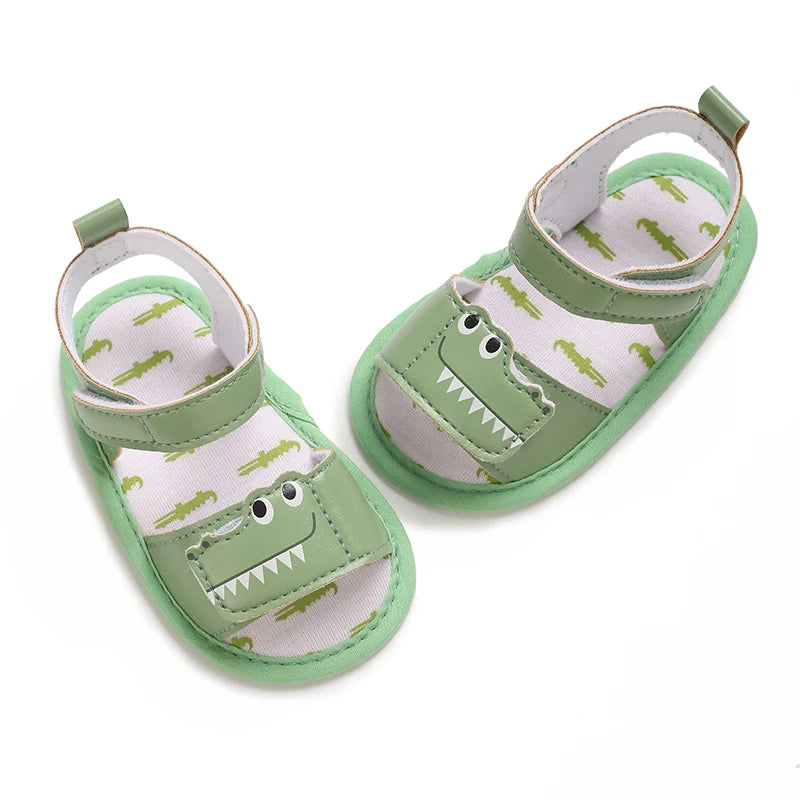 Top angled view of green baby crocodile sandals with an alligator print on the inner sole.