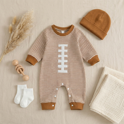 Flat lay outfit featuring the baby boy striped football romper alongside a matching brown beanie, baby socks, and a wooden rattle.