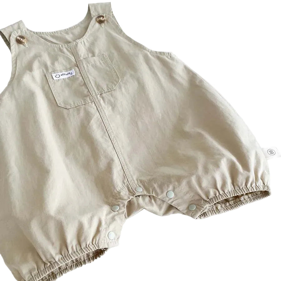 Close up of the lower half of the Hamptons Beige baby overalls showing the relaxed bubble fit legs and closed snap bottom.