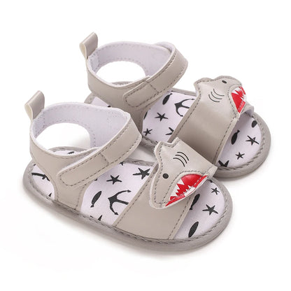 Pair of grey baby boy shark sandals featuring a layered cutout shark face and adjustable straps.