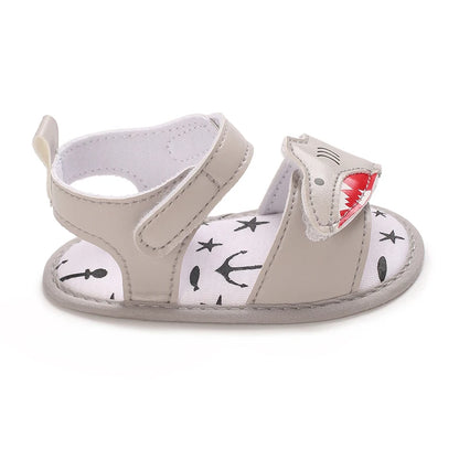 Side view of a grey infant first walker sandal highlighting the layered shark design and strap.