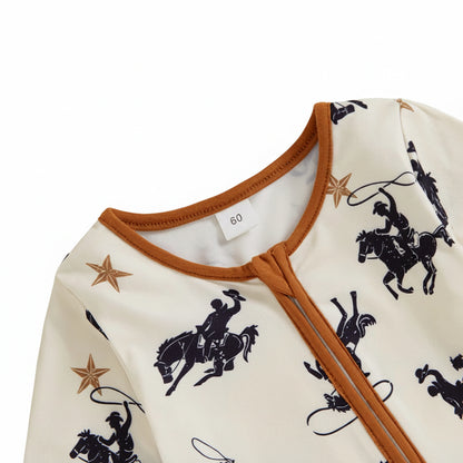 Close-up of the round neckline and closed diagonal zipper with a protective fabric zipper guard on the western cowboy print baby romper.