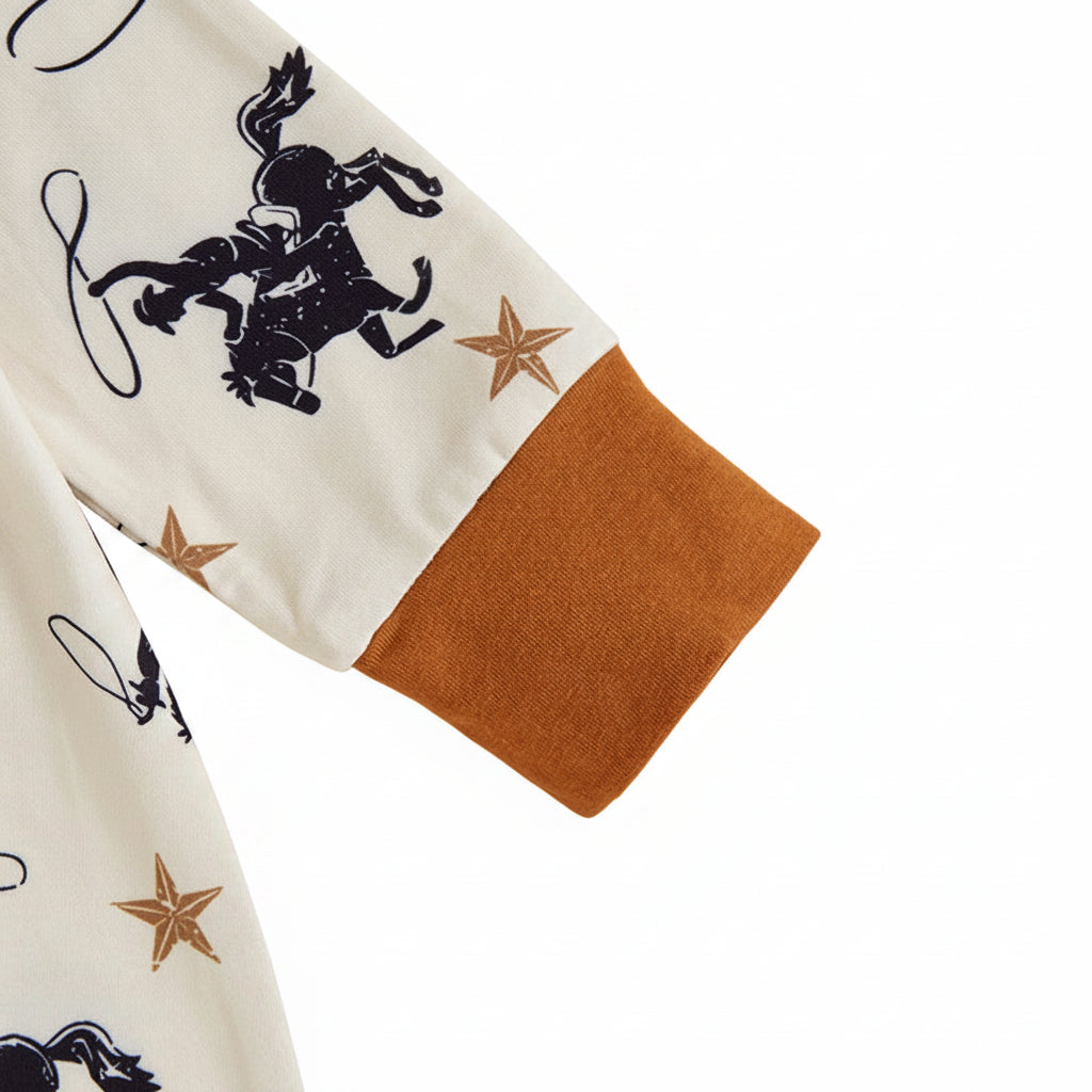 Close-up of the long sleeve featuring a contrasting brown wrist cuff and star print on the infant western cowboy jumpsuit.