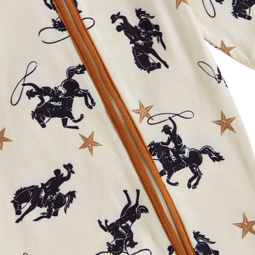 Close-up detail of the smooth diagonal zipper running across the chest, highlighting the lone star, horse, and lasso cowboy print on the baby boy jumpsuit.